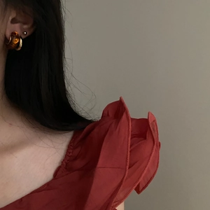 Close-up of vintage amber resin C-shape earring worn by model for retro style look