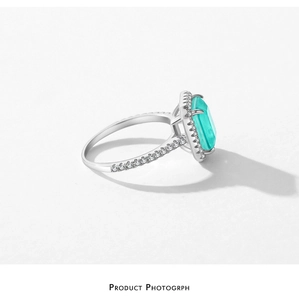 Macro shot of silver ring featuring a rectangular blue-green stone and halo diamond setting