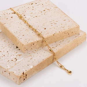Minimalist double layer vintage gold bead chain bracelet on textured sandstone display