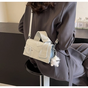 Détail d'un sac à main en cuir blanc crème avec rabat asymétrique et poignée nouée