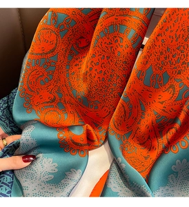 Détail macro d'un foulard soyeux bleu et orange avec des motifs de dentelle complexes