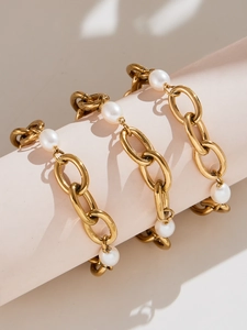 Detailed view of high-polished gold chain bracelet with pearls on display stand