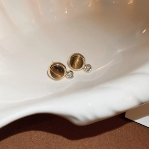 Dettaglio di orecchini vintage dorati con finta pietra occhio di tigre marrone e zircone