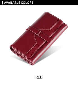 Detail of red oil wax leather wallet featuring white stitching and secure strap closure