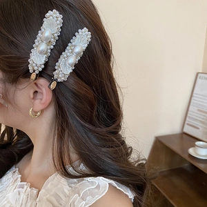Detail of elegant pearl hair clips worn on side hair with golden metal base