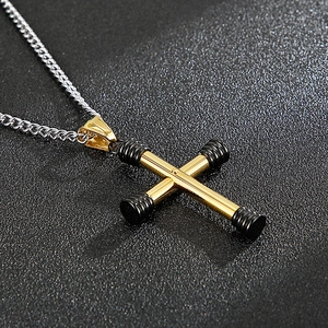 Detailed close-up of a golden cross dumbbell pendant on a silver metal chain necklace