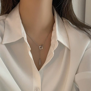 Silver geometric necklace with square pendant shown on a model wearing a white shirt