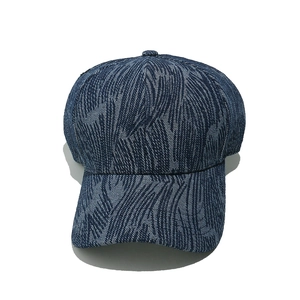 Detail of navy blue denim baseball cap with white palm leaf stripes and curved brim