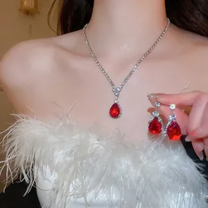Luxurious silver necklace and drop earrings set with pear-cut red gems and zircon stones