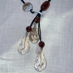 Détail du collier bohème avec plumes dorées et perles en résine d'ambre