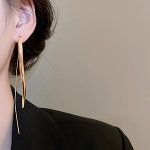 Close-up of elegant golden teardrop earrings on model with sleek metallic finish