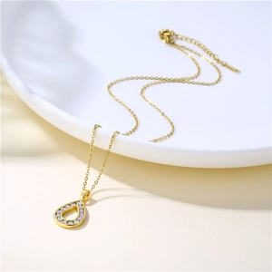 Gold water drop necklace with clear zircon pendant on a white ceramic dish