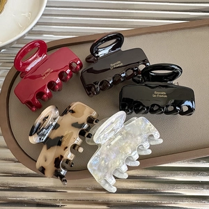 Set of five French acetate shark hair clips in assorted colors on a minimalist tray