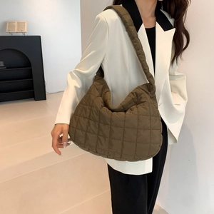 Deep olive green quilted puffer tote bag shown with minimalist white blazer styling