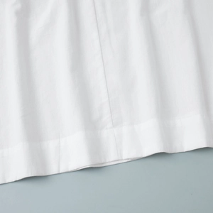 Detailed close-up of high-quality white cotton fabric hem with precise stitching finish
