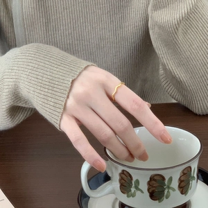 Minimalist golden wave ring in 925 silver worn by a model holding a vintage coffee cup