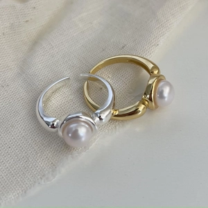 Detailed view of silver and gold pearl rings on textured white linen fabric