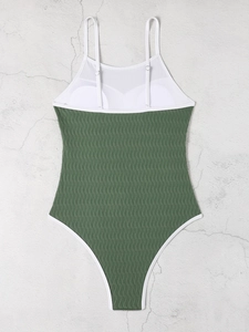 Macro detail of olive green textured fabric and white mesh panels of the one-piece swimsuit