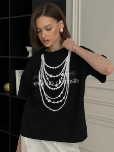 Detailed view of pearl necklace print and precious deposits text on black cotton T-shirt
