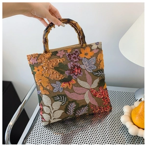 Detailed view of vintage linen handbag featuring bamboo handles and floral sequin embroidery