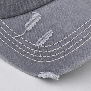 Close-up of distressed grey cotton baseball cap with thick white contrast stitching