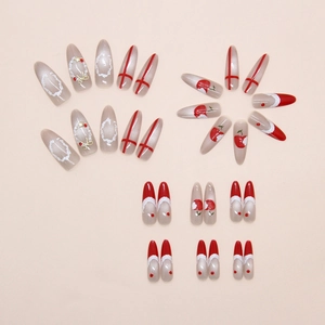 Detail of almond press-on nails with red French tips, cherry art, and gold 3D bows