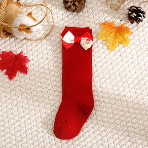 Close-up of red Christmas baby socks with Santa Claus decor and festive ribbons