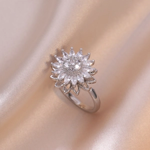 Close-up of sparkling silver sunflower ring with clear zircons on beige satin background