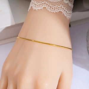 Detail of elegant slim gold-plated minimalist ring bracelet on model wrist