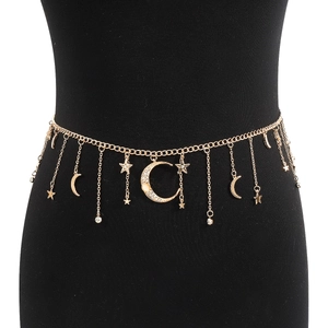 Detail of layered gold moon and star body chain with pearls on a black mannequin