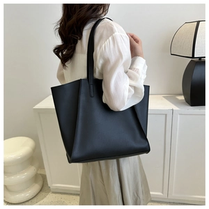Side view of large black PU leather tote bag shown on a minimalist indoor display
