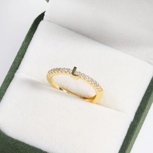 Macro shot of 18k gold plated brass ring with diamond L-letter in a green velvet box