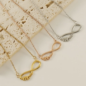 Trois colliers MAMA infini en or, or rose et argent disposés sur une pierre texturée