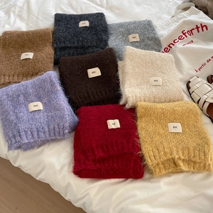 Detailed macro view of soft wool blend knit scarves in multiple colors with white labels