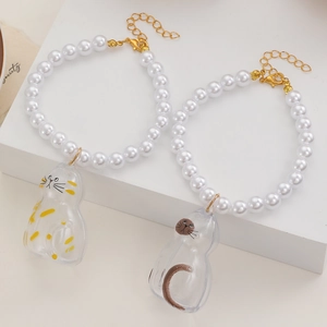 Detailansicht der Perlenarmbänder mit transparenten Katzenanhängern und Goldverschluss