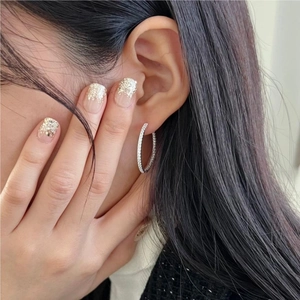 Close-up of a silver large hoop earring with shimmering zircons worn by a model