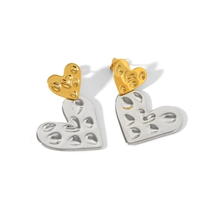 Detailed view of dual-tone 18K heart earrings with hammered texture on white background