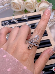 Detail of safety pin ring with cubic zirconia stars on female model's finger