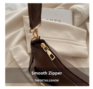 Close-up of smooth gold metal zipper and premium brown leather texture on handbag
