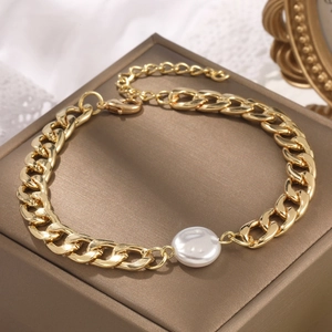 Detailed close-up of a gold link chain bracelet featuring a large baroque pearl center