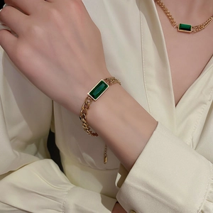 Détail d'un ensemble élégant bracelet et collier en or avec pierres rectangulaires émeraude