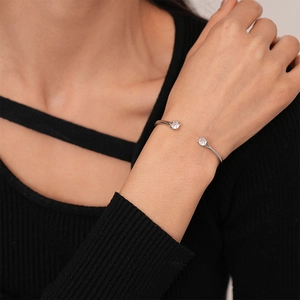 Close-up of minimalist silver open cuff bracelet with zircon flower stones on wrist