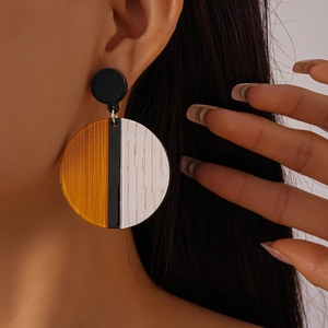 Close-up of model wearing geometric circular acrylic earrings with wood grain texture