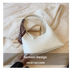 Detail view of cream hobo bag featuring a decorative printed silk scarf on handle