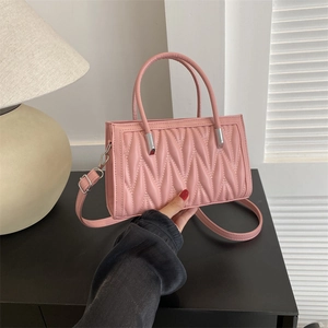 Pink top-handle bag with V-shaped quilting and a detachable shoulder strap