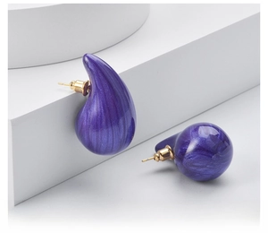 Close-up of purple teardrop earrings with marble texture and golden metal pins
