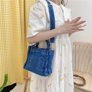 Blue denim crossbody bag featuring contrast stitching worn with a white floral dress