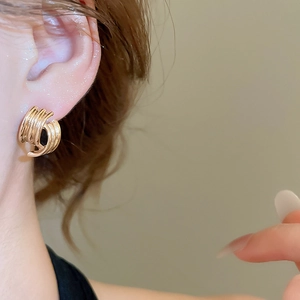 Close-up of geometric gold layered arc earrings with a minimalist metallic spiral design