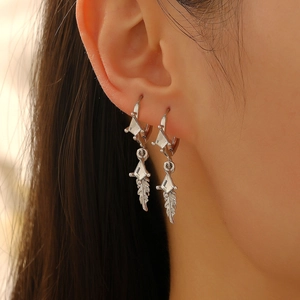 Cool silver feather drop earrings with geometric zircons worn by a fashion model