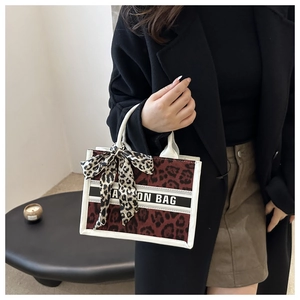 Detail of burgundy leopard print canvas tote bag with white handles and patterned silk scarf
